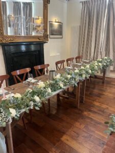 Room layout, unclothed trestle tables and floral decoration for all-inclusive wedding at The Greyhound Coaching Inn Lutterworth