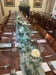 Room layout, unclothed trestle tables and floral decoration for all-inclusive wedding at The Greyhound Coaching Inn Lutterworth