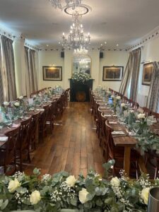 Room layout, unclothed trestle tables and floral decoration for all-inclusive wedding at The Greyhound Coaching Inn Lutterworth